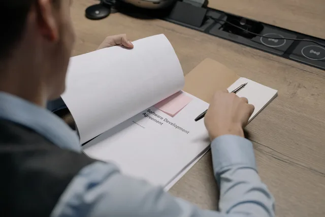 Business professional at the desk examining a software development agreement document. Selecting franchise software with requirements that can fail